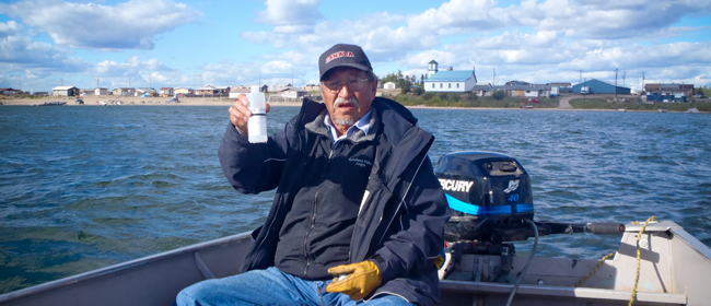 Elder Joe Marten from Fond du Lac collecting a water sample<br>Photo courtesy of CanNorth